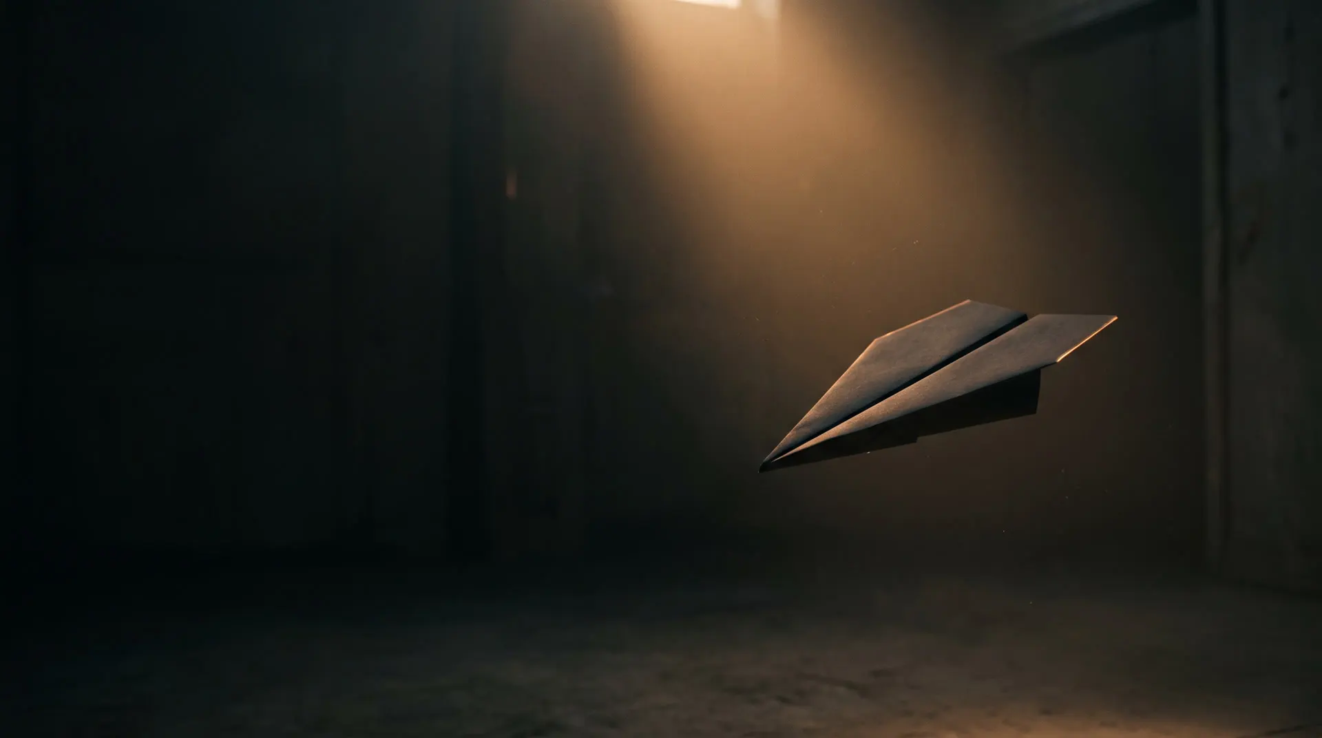 A paper plane crossing a beam of amber light in a dark studio